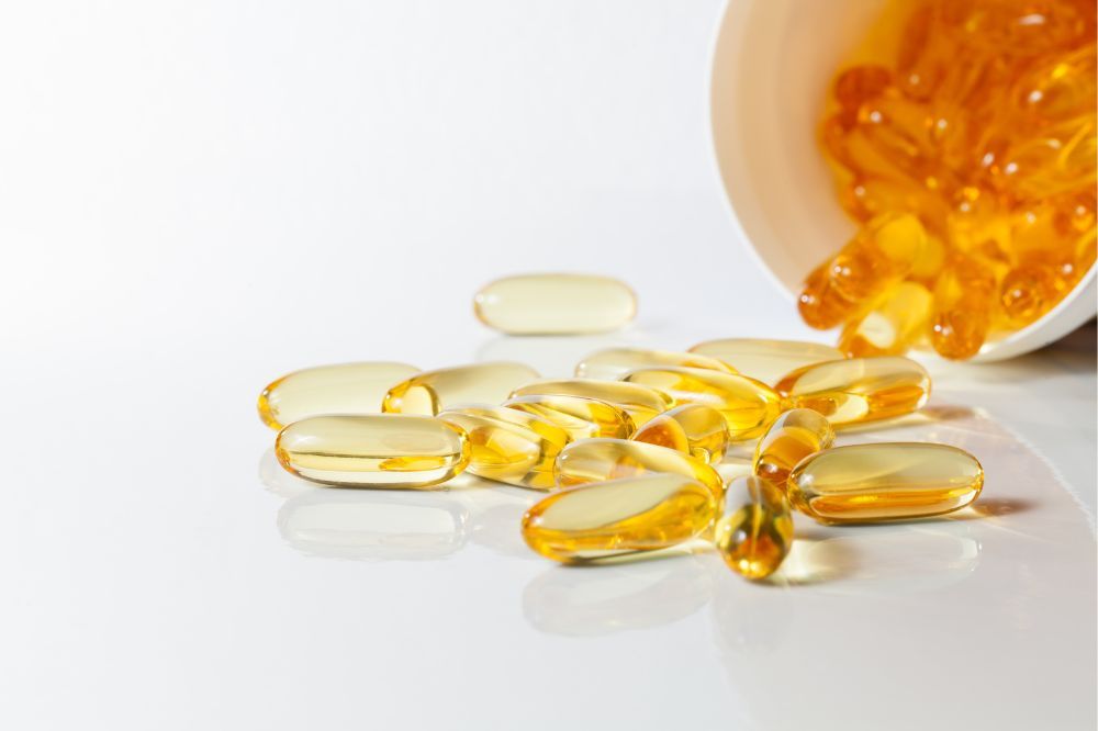 DHA a EPA - omega-3 mastné kyseliny. Rozsypané oranžové kapsule omega 3.