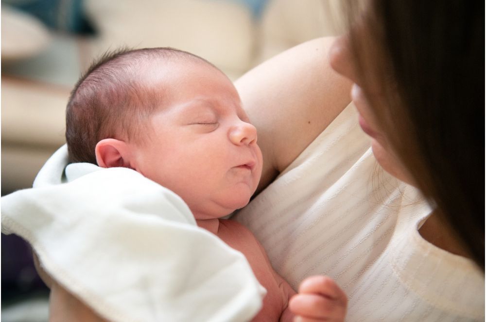 Mamička drží v rukách kojenca, ktorého detská imunita ešte nie je vyvinutá.