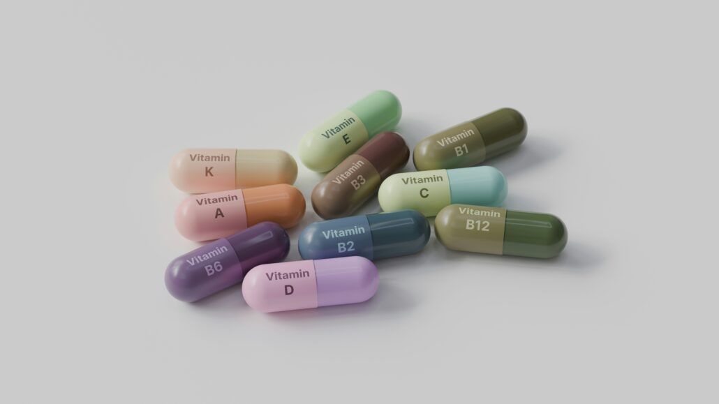 Na sivom podklade ležia rôznofarebné kapsule označené názvom vitamínu, ktorý obsahujú a ktorý v kombinácií s iným vitamínom alebo minerálom môže tvoriť synergický efekt.