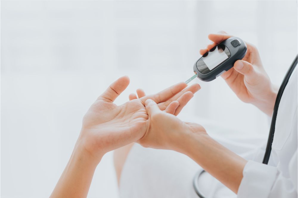 Pohľad na ženskú ruku a lekára, ktorý pomocou prístroja meria krvný cukor, pretože pankreas plní úlohu regulácie krvného cukru.