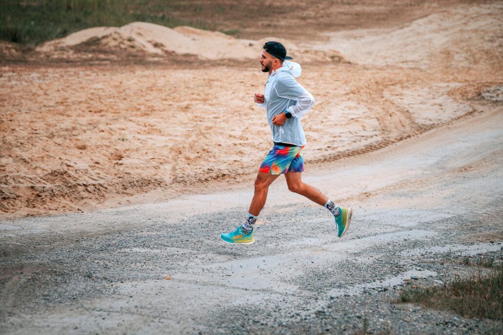 Športovec beží po asfaltovej ceste v nízkej intenzite, ktorá je dôležitá pre zvýšenie výkonnosti a následne po tréningu si potrebuje dopriať regeneráciu svalov. 