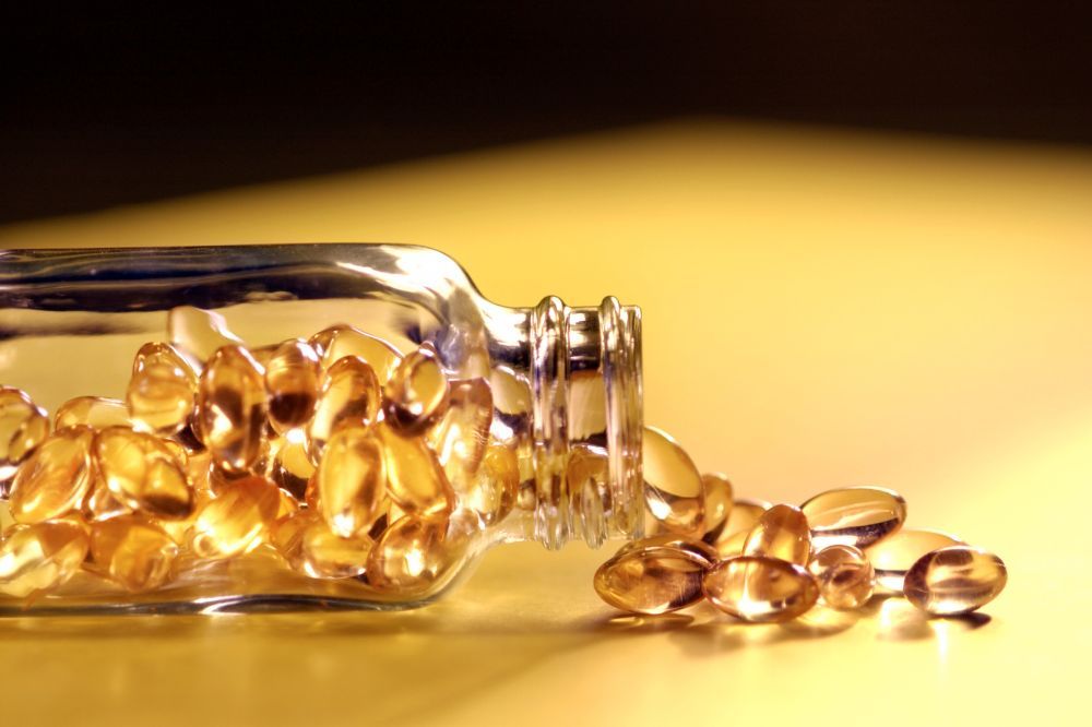 Sklenená flaška s rozsypaným vitamínom E, ktorý má priaznivé účinky pri cukrovke a má pozitívne účinky na mozgovú činnosť, leží na podlahe.