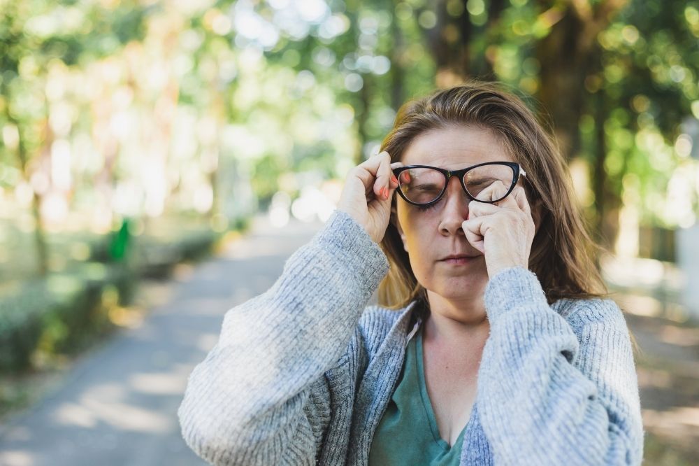 Jarná únava - letergia, žena v okuliaroch na ulici si pretiera oči
