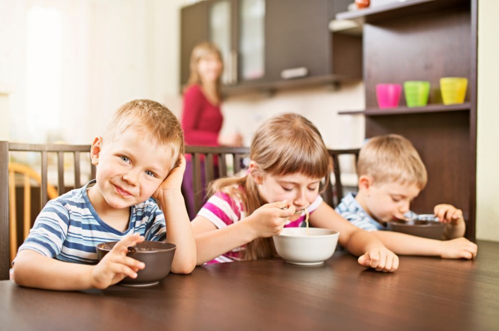 Deti sedia za stolom v škôlke aj jedia jedlo plné vitamínov, ktoré potrebujú pre svoju detskú imunitu.