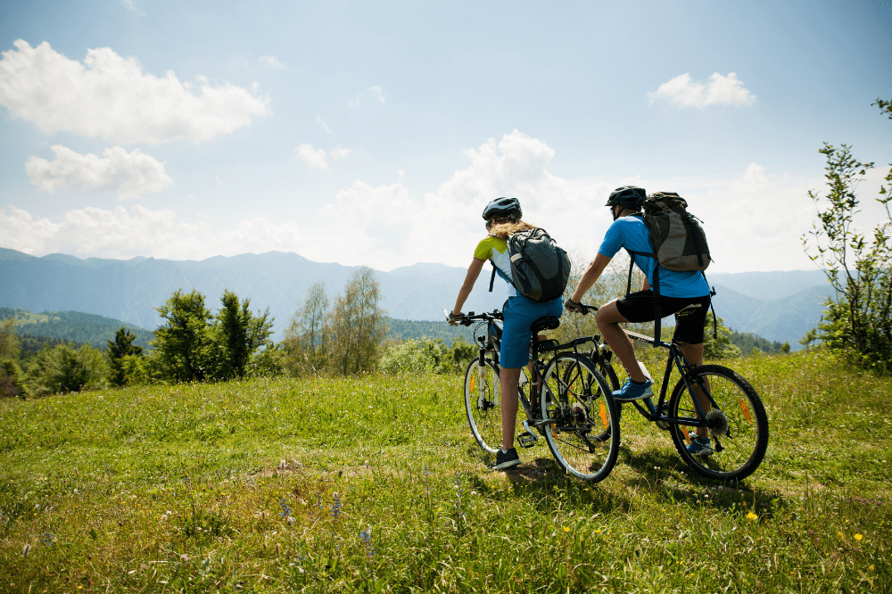 Pár na horských bicykloch v prírode ako príklad letného športu, ktorý posilňuje kolená a šetrí kĺby