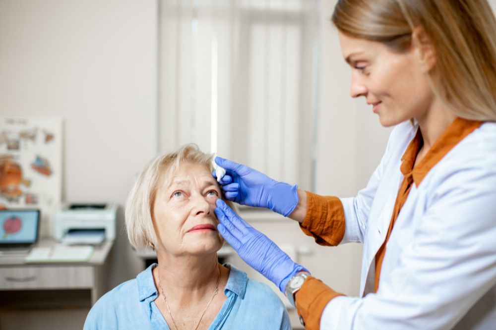 Lekárka kvapká roztok staršej pacientke do očí, pretože má podráždené oči v dôsledku zápalu oka.