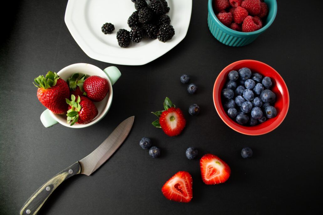 Na čiernom stole sú misky plné bobuľovitého ovocia, ktoré je zdrojom polyfenolov, ktoré dodávajú ovociu intenzívnu farbu a majú pozitívny vplyv na ľudské zdravie.