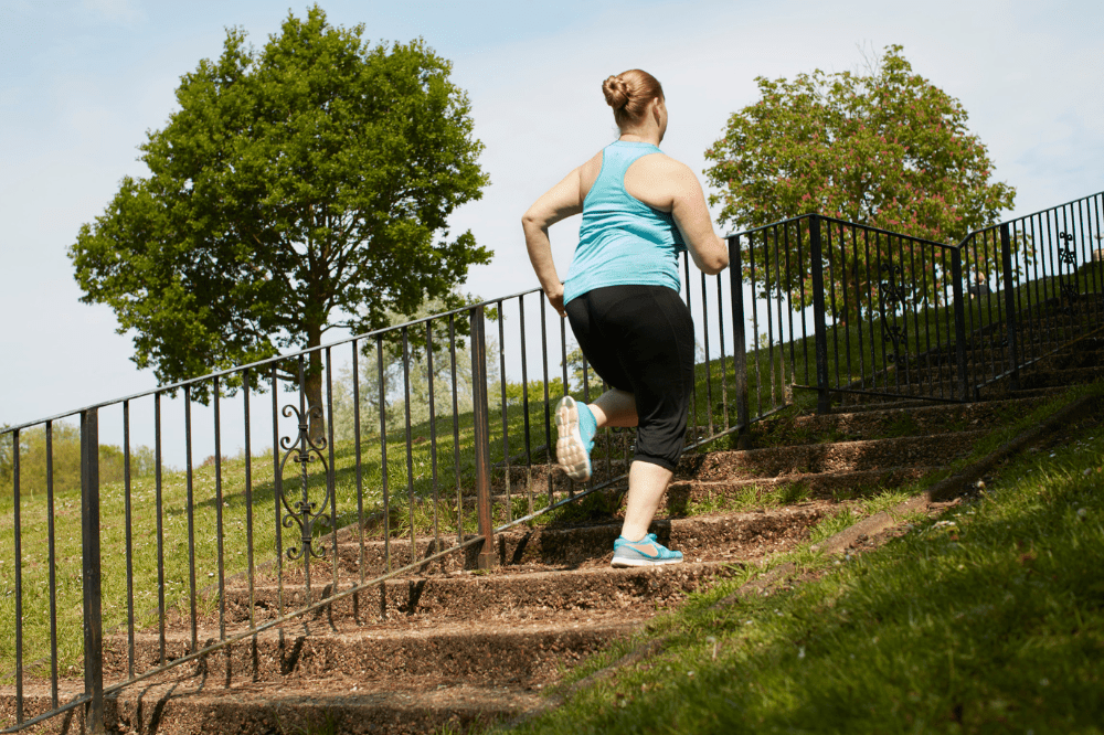Žena beží po schodoch a športuje, pretože má stukovatenú pečeň a pohyb je jedným z faktorov, ktoré jej môžu pomôcť, aby sa z toho dostala.