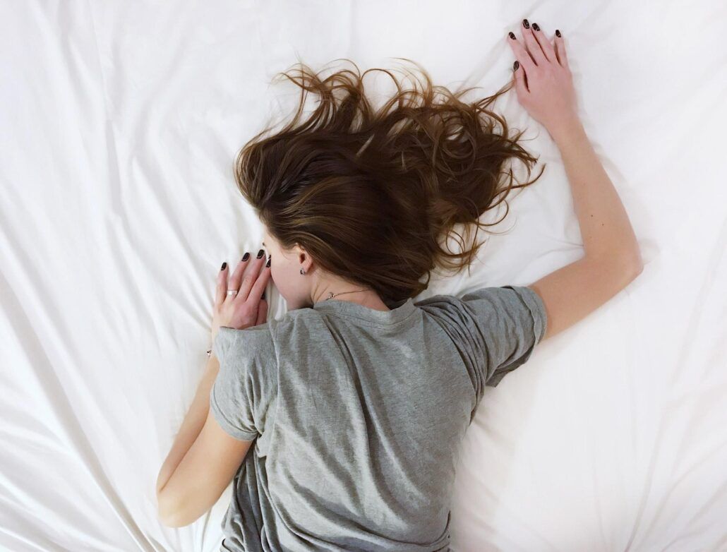 Hypersomnia (spavosť) - spiaca žena na posteli otočená chrbtom