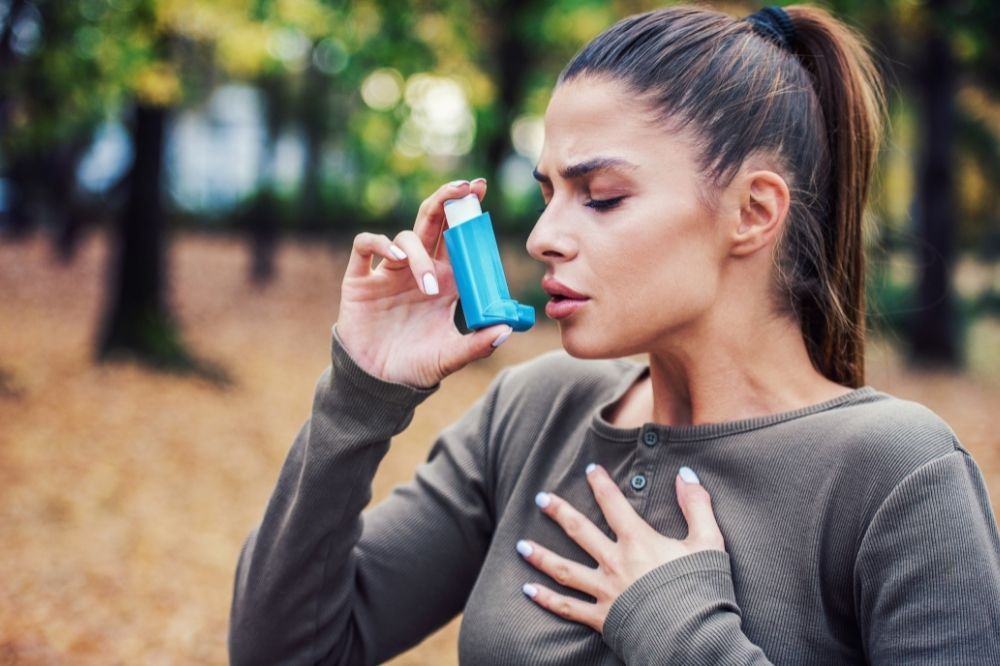 Selén môže pomôcť zmierniť sprievodné príznaky astmy. Žena sa drží za hrudník a užíva sprej proti astme.