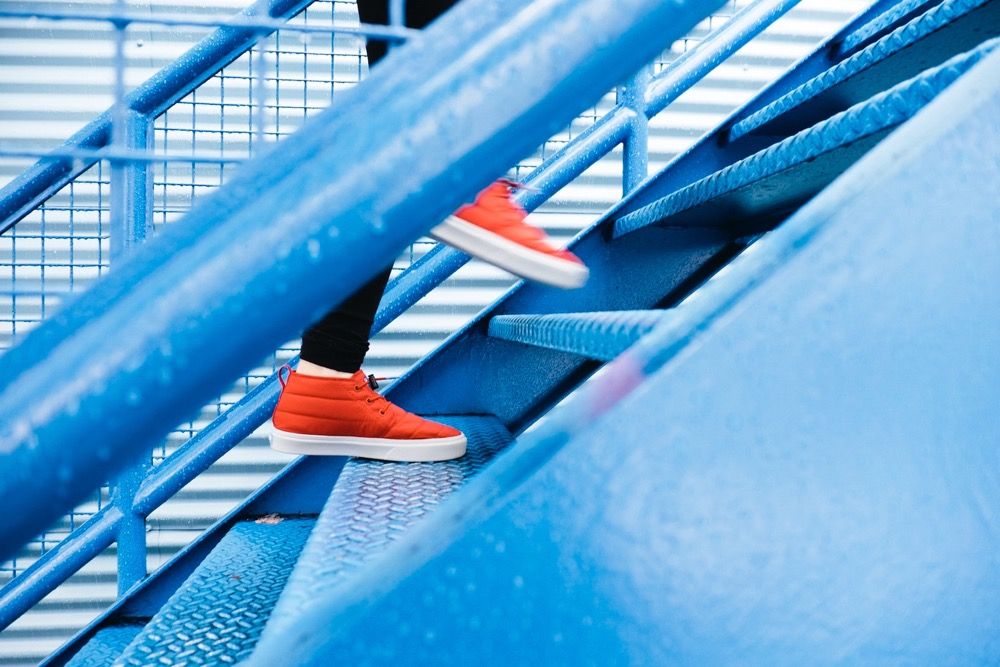 Nedostatok draslíka - osoba v červených teniskách beží hore modrými kovovými schodmi