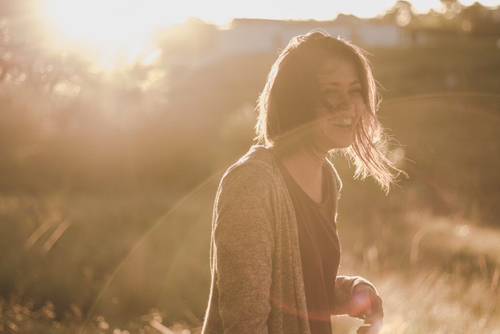 Nezaťažujte imunitu - vitamín d. Žena s úsmevom na tvári si užíva slnečné lúče.