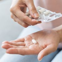 Pohľad na ruku, na ktorej sú antibiotiká, ku ktorým je vhodné brať orálne probiotiká ako podporu.