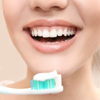 Žena si čistí zuby usmieva sa, pretože k ústnej hygiene dopĺňa aj orálne probiotiká, ktoré jej pomáhajú podporiť sliznicu ústnej dutiny.